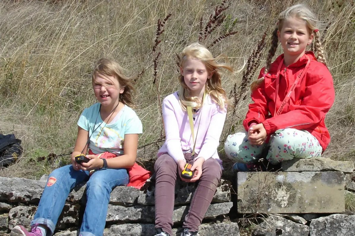 Drei Kinder sitzen auf einer Mauer